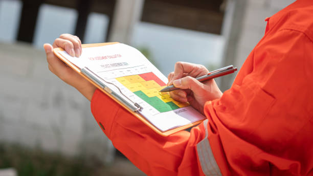 Project engineer is rating on risk assessment. Action of the project engineer is rating on risk assessment form to evaluate the project investment progression with background of construction building. Business financial concept scene. scrutiny stock pictures, royalty-free photos & images
