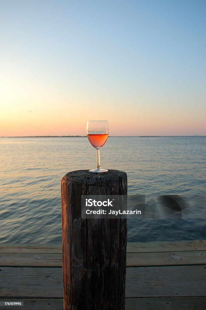 Rose Wine Füllung Glas auf bay, pier im Sonnenuntergang - Lizenzfrei Wasserrand Stock-Foto