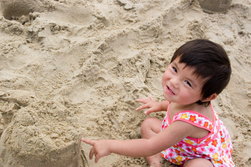 Asian little girl playing in the sand at beach