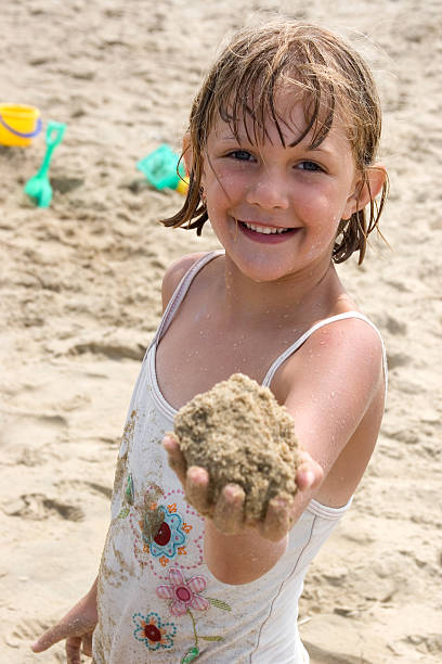 istock Girl with handful of sand 176103190