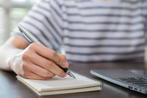 istock Close-up of hand writing on blank notebook on table. 1761045339