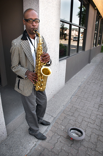 Sax player jamming for tips on the sidewalk. Need photos representing music