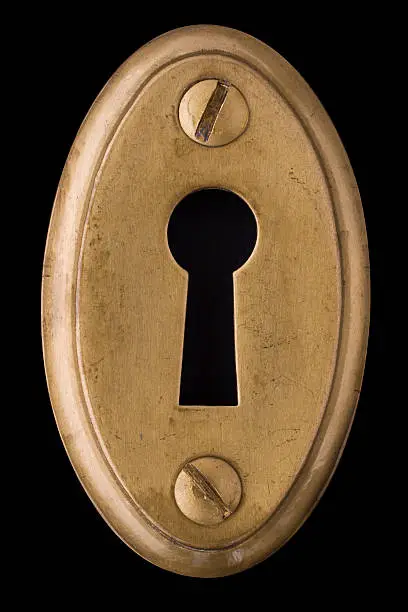 Brass keyhole against black background.