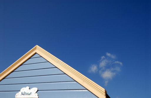 An abstract view of a beach hut roof and fluffy white cloud.