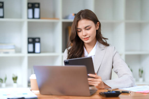 istock Smiling and attractive asian businesswoman enjoying working using laptop computer at office. 1761094847