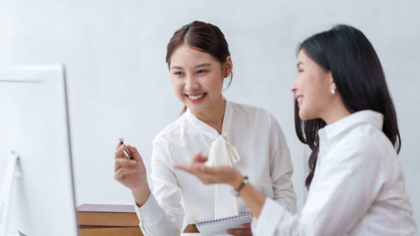 istock Two beautiful Asian young business women discuss work exchange idea exchange knowledge using laptop computer in the office. 1761100301