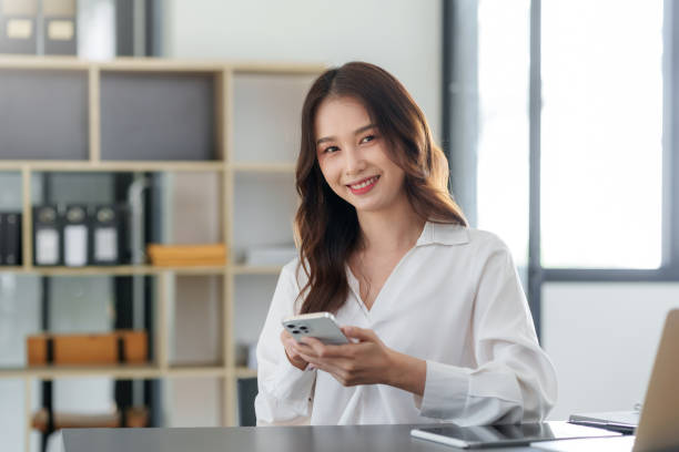 istock Smiling Asian businesswoman using smartphone at office. 1761109347