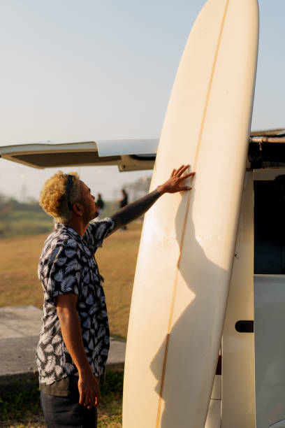 istock Indonesian Surfer Arranging Surfboard near a Camper Van at Sunset 1761111240