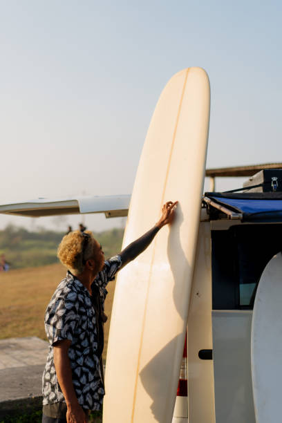 istock Indonesian Surfer Arranging Surfboard near a Camper Van at Sunset 1761111274