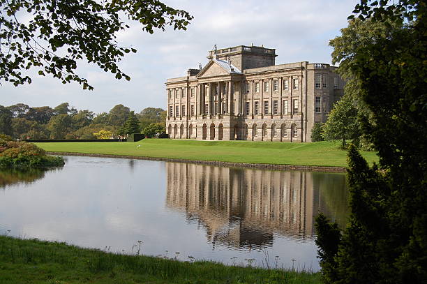 Typical English Mansion House And Moat Image of a traditional large English mansion house with portico entrance. In the foreground a lake moat with reflection of the mansion hall. Lyme Park Hall, Cheshire, UK. national trust photos stock pictures, royalty-free photos & images