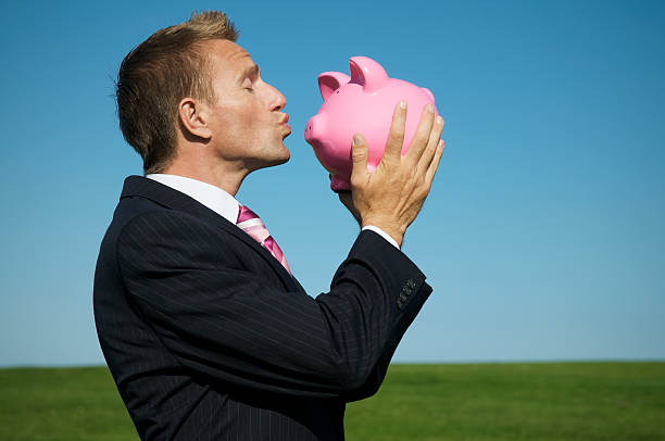 młody człowiek biznesmen całować różowa świnka skarbonka - caucasian three dimensional shape men sky zdjęcia i obrazy z banku zdjęć