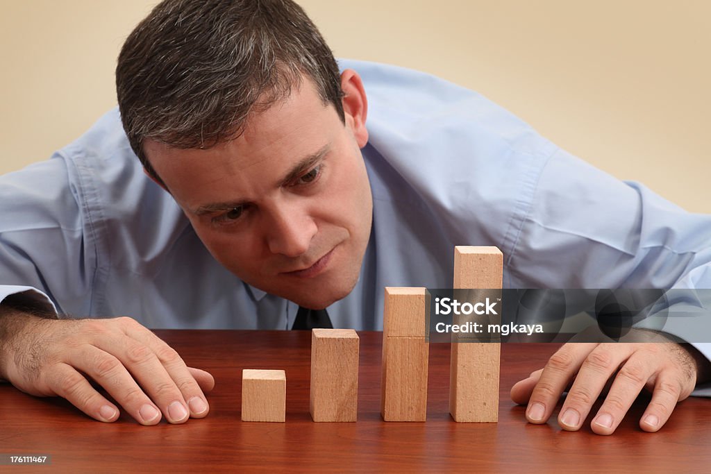 Analyzing Bar Graph Businessman looking at the increasing bar chart made with wooden blocks. Achievement Stock Photo