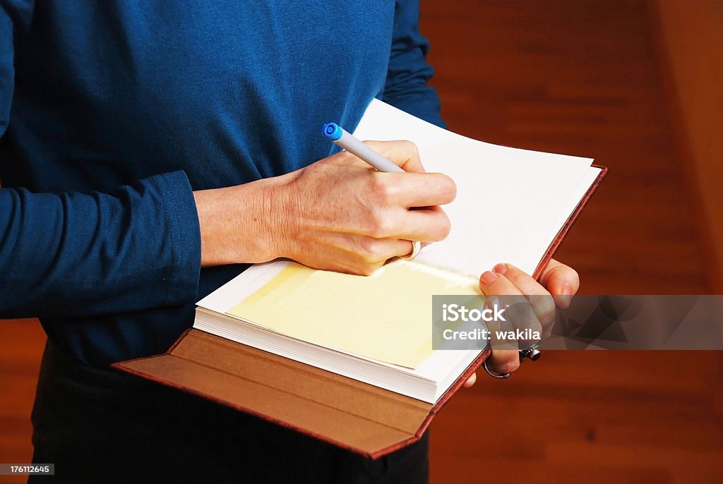 Escrevendo em um livro-mulher em pé - Foto de stock de Acordo royalty-free