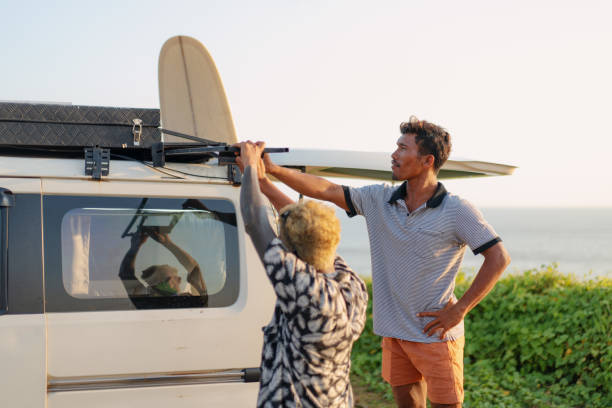 istock Two Friends Setting Up Tent on top of a Camper Van at Sunset 1761129928
