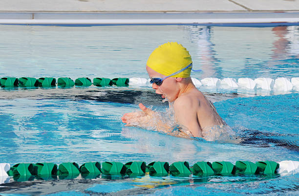junge männliche junge brustschwimmen schwimmer in race - breaststroke stock-fotos und bilder