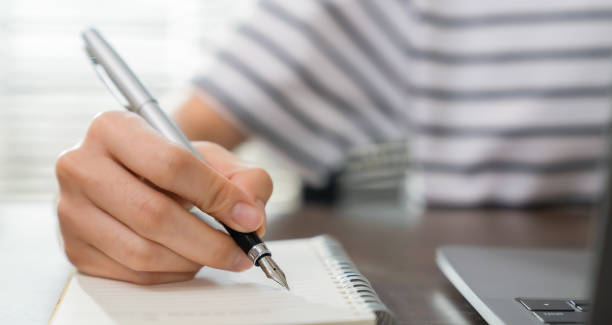 istock Close-up of hand writing on blank notebook on table. 1761146340