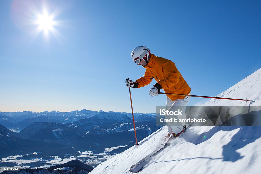 skiing down steep mountain male skier on his way down on steep hill in front of mountain panorama Activity Stock Photo