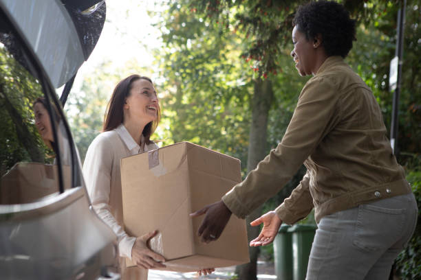 istock Two cheerful women unloading a cardboard box from the back of a car 1761184723
