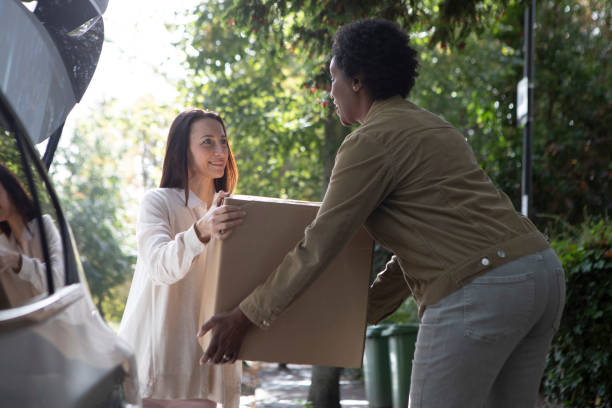 istock Two cheerful women unloading a cardboard box from the back of a car 1761185274