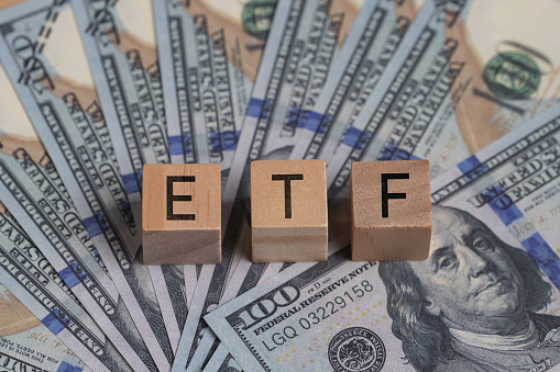 Concept words ETF on wooden blocks, acronym ETF which refers to Exchange Traded Fund inscribed on wooden cubes United States dollars. Economy and investments.