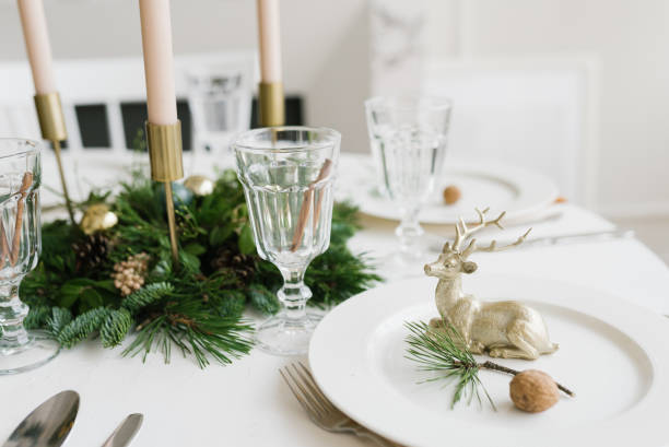 istock Christmas or new year table setting. Plates, silver Cutlery, glasses, gift box, festive branch decoration, candles, shiny deer on a white table background, selective focus 1761194023