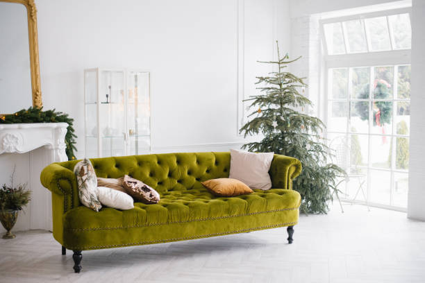 istock The green velour sofa with pillows in the bright attic room has an artificial fireplace.A spacious living room with white walls and a decorated Christmas tree 1761197789