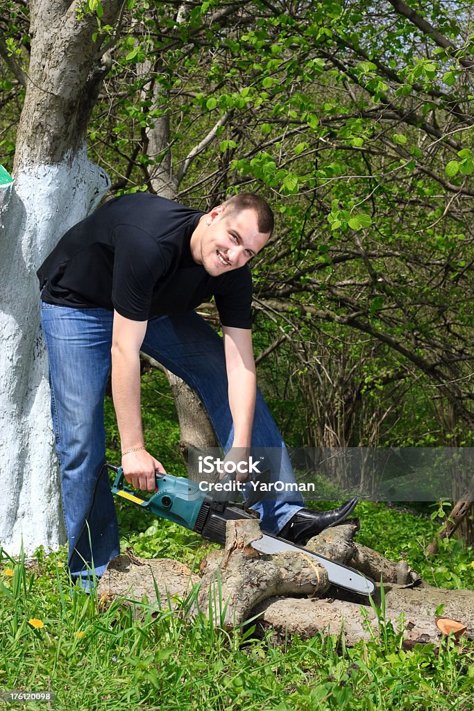 Lächelnder Mann im Frühling Garten Sägen Protokolle electric Kettensäge - Lizenzfrei Arbeiten Stock-Foto