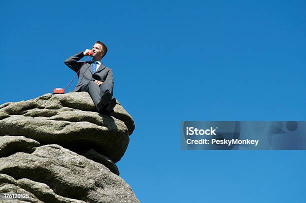 Biznesmen Siedzi Na Zewnątrz Górnej Części Rock Rozmawia Przez Telefon - zdjęcia stockowe i więcej obrazów Góra