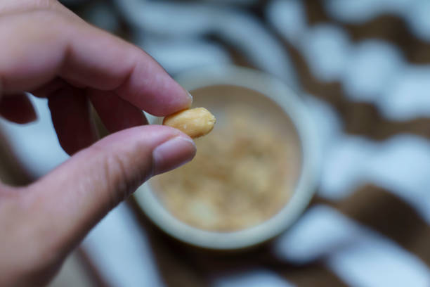 istock A hand takes salted peanuts or beans out of a ceramic cup. 1761204878