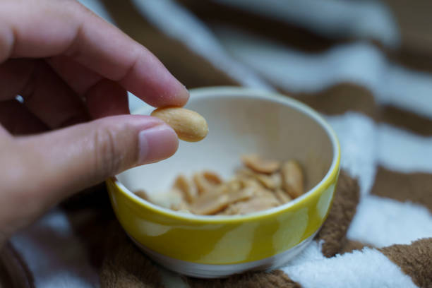 istock A hand takes salted peanuts or beans out of a ceramic cup. 1761205977