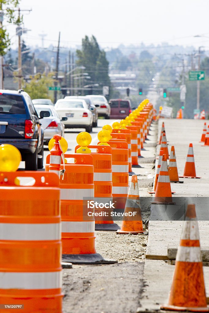 Construction and Traffic A row of bright Orange construction barriers stretching off into the distance separates construction from the busy traffic. Road Construction Stock Photo