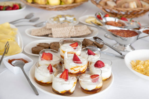 Light breakfast with focus on small yogurt and salted caramel cups enjoyed with fresh strawberries, healthy morning snack or indulgent dessert with tasty seasonal fruit, at a self-service buffet bar.