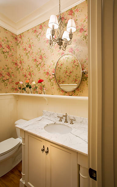 Traditional powder room with white marble. "Traditional powder room/guest bathroom with white marble vanity top, white enamel crown moulding and flowered wall paper print." powder room stock pictures, royalty-free photos & images