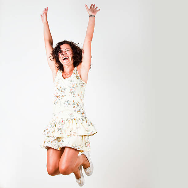 Mature adult woman laughing and jumping on white background. She looks so funny! Some blur due to the movement.