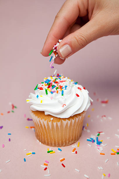 sprinkling sprinkles on cupcake sprinkling sprinkles on cupcake sprinkling stock pictures, royalty-free photos & images