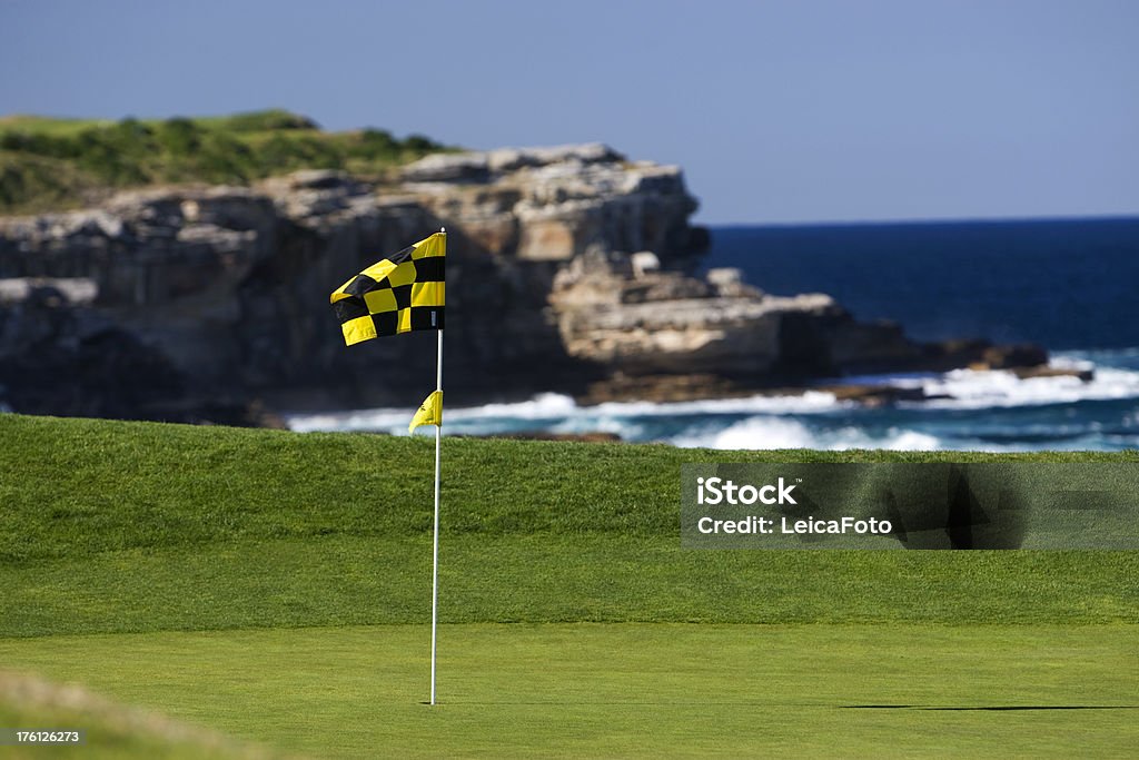 Golf Flag A golf flag blows in the wind on a beautiful golf course by the ocean. Blue Stock Photo