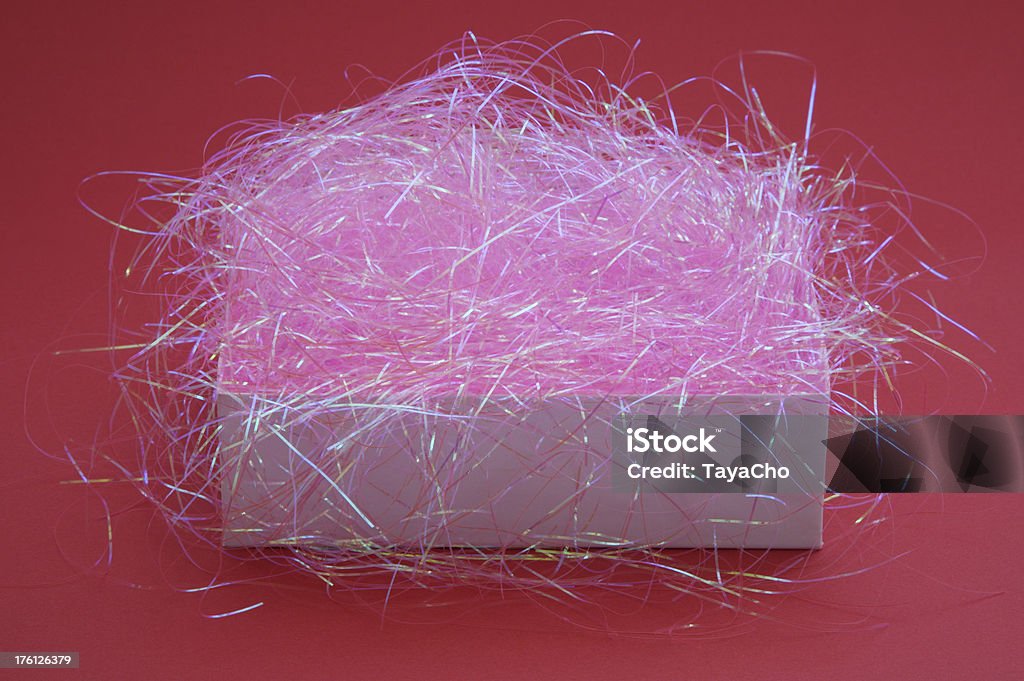 Open gift box with pink stuffing White gift box  with pink tinsel stuffing on a red background. Beauty Stock Photo