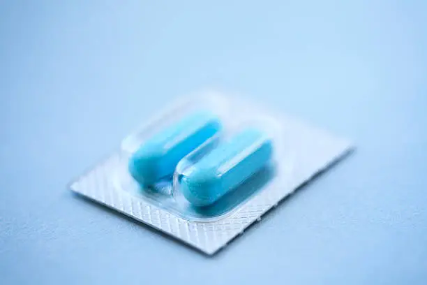 Single blisterpack containing two pills on a blue background. Cool tones.