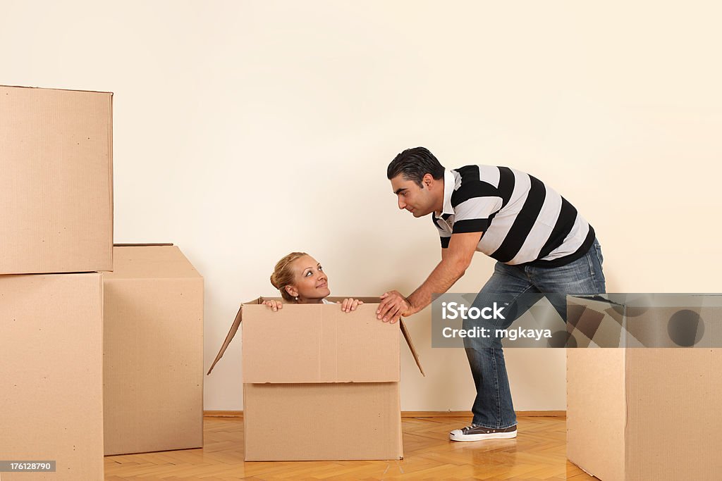 Happy Young Couple Young couple having fun at the moving day. Man pushing cardboard box with woman. 25-29 Years Stock Photo