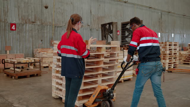 inspector explains a piece to a worker in a pallet wood factory.