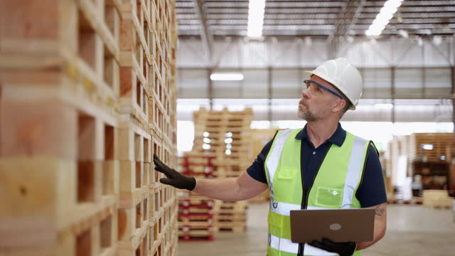 worker or inspector is checking the quality and quantity of goods in a pallet wood factory.