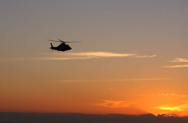 istock Silhouetted helicopter flies towards a rising sun 176130995