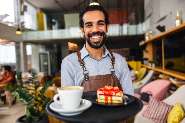istock Confident Middle Eastern Male Bartender Smiling At The Camera While Holding A Drink Tray In A Charming Cafe 1761310440