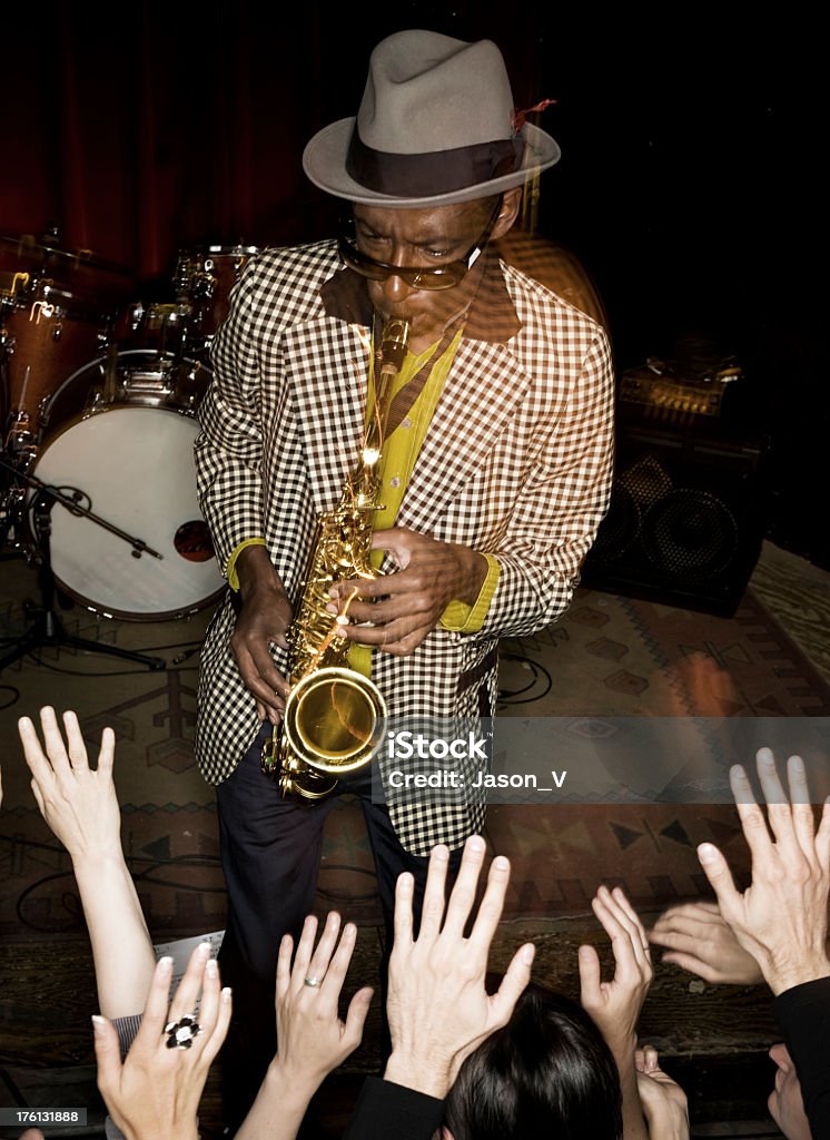 Sax Player with a crowd A sax player with a crowd below him.  There is intentional motion blur (shutter drag) due to slow shutter speed and high flash speed Ska Stock Photo