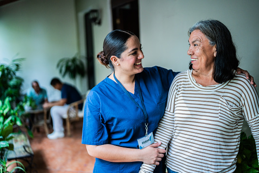 Home caregiver talking to a senior woman at nursing home