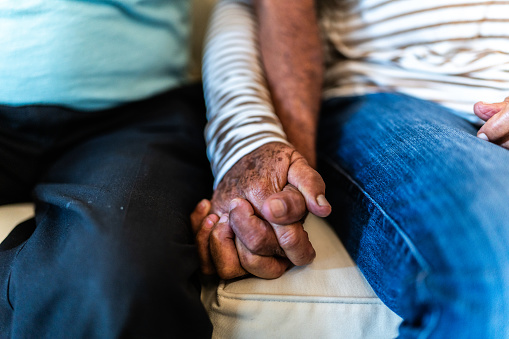 Close-up of a senior couple holding hands sitting on sofa