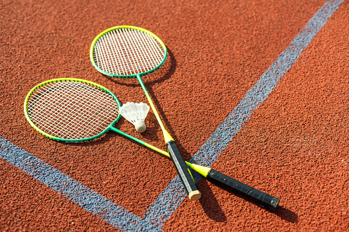 Badminton shuttlecocks and racket, placed in the corner of a synthetic field. High quality photo