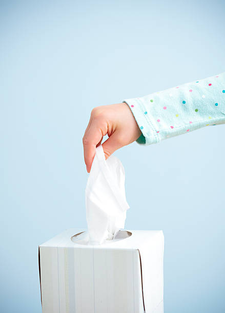 Child hand pulling tissue out of box stock photo