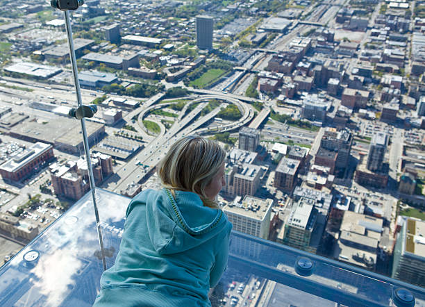 Tourist admiring view of Chicago from Sears Tower "A young tourist admiring view of Chicago from the new tourist attraction- glass , ""see-through"" ledges at Sears Tower( Willis Tower).... not for the faint hearted since it's 412m above the groundCheck out my Chicago Lightbox with more images:" willis tower stock pictures, royalty-free photos & images