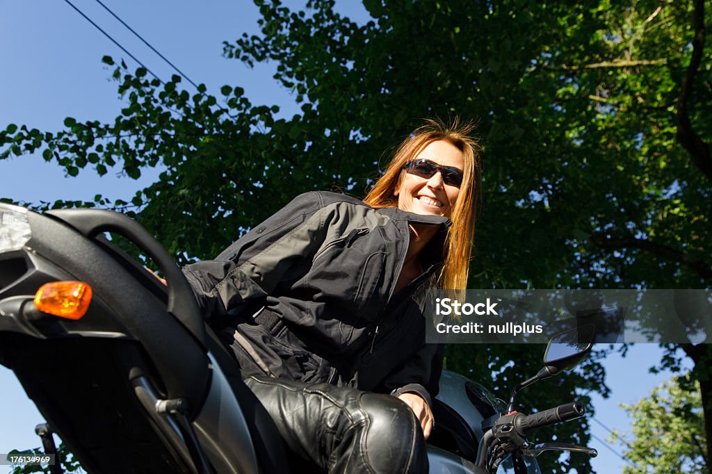 adult woman riding her motorcycle an adult woman is sitting on her motorcycle, looking at the camera. 40-49 Years Stock Photo